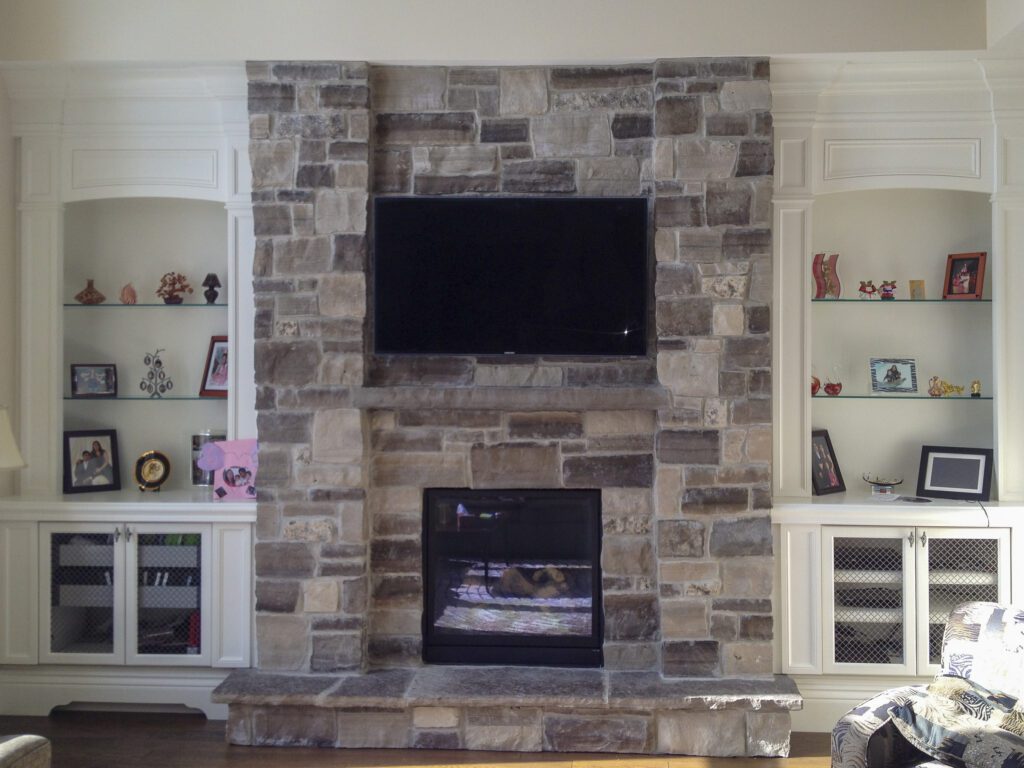 A stone fireplace flanked by built-in cabinetry in Stouffville.